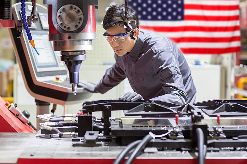 worker at a manufacturing facility with an american flag in the background